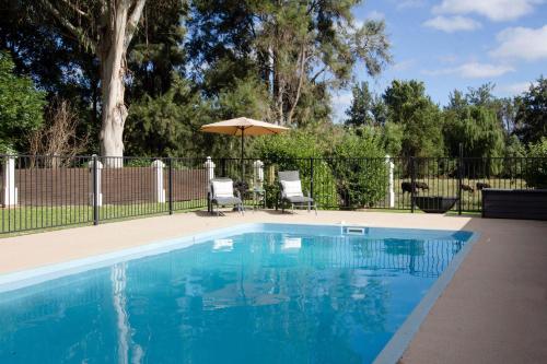 a swimming pool with two chairs and an umbrella at Mudgee Country Grandeur at this Elegant Group Getaway in Mudgee