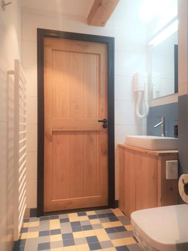 a bathroom with a wooden door and a sink at 23 SouS in Amsterdam