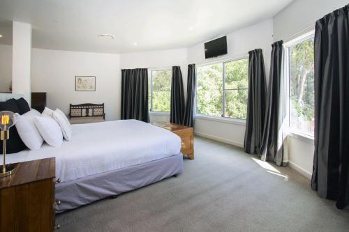 1 dormitorio con 1 cama blanca grande y ventanas en Mudgee Country Grandeur at this Elegant Group Getaway en Mudgee