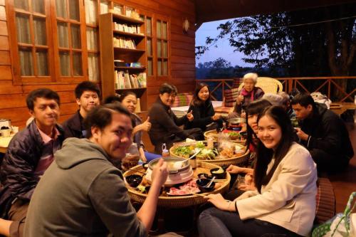 a group of people sitting around a table eating food at Ashi Guesthouse Chiangdao in Chiang Dao