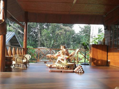 a woman sitting in a chair on a porch at Ashi Guesthouse Chiangdao in Chiang Dao