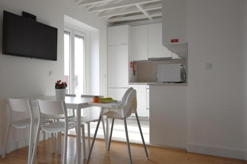 a white kitchen with a table and white chairs at Ocean View Penthouse in Paço de Arcos