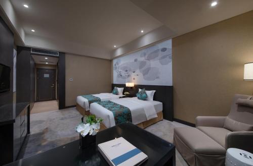 a hotel room with two beds and a couch at Shenyang Huaqiang Novlion Hotel in Daoyi
