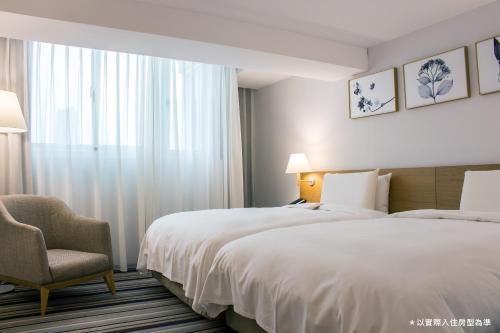a hotel room with two beds and a chair at The Carlton Taichung in Taichung