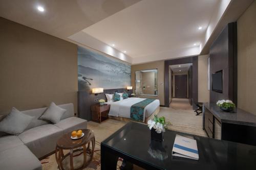 a hotel room with a bed and a couch at Shenyang Huaqiang Novlion Hotel in Daoyi