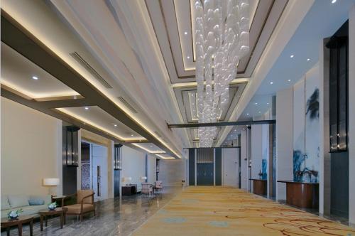 a lobby with a long hallway with a chandelier at Shenyang Huaqiang Novlion Hotel in Daoyi