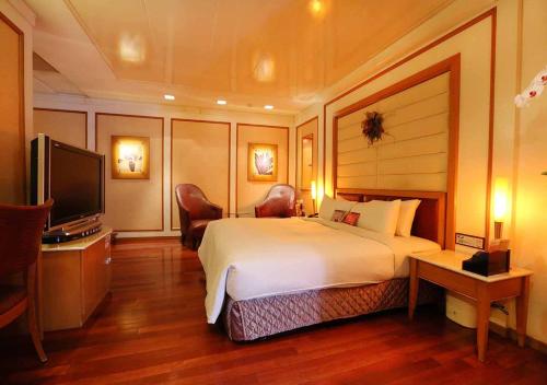 Habitación de hotel con cama grande y TV en Royal Group Motel Tainan Branch, en Tainan