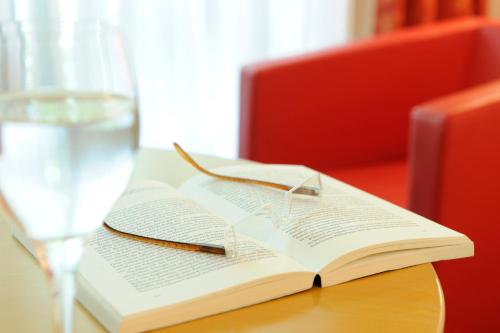 an open book on a table with a glass of water at Johannesbad Hotel Königshof in Bad Füssing