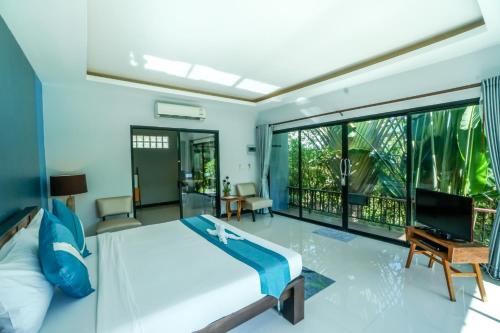 een slaapkamer met een bed en een groot raam bij Himaphan Boutique Resort - SHA EXTRA PLUS in Nai Yang Beach