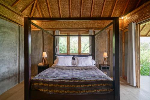 a bedroom with a canopy bed with two lamps at Pondok Manoka in Kintamani