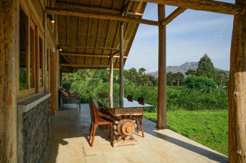 an open porch of a house with a table and a chair at Pondok Manoka in Kintamani