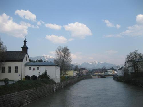 a river in a town with a church and a bridge at Hotel Hafnerwirt in Hallein