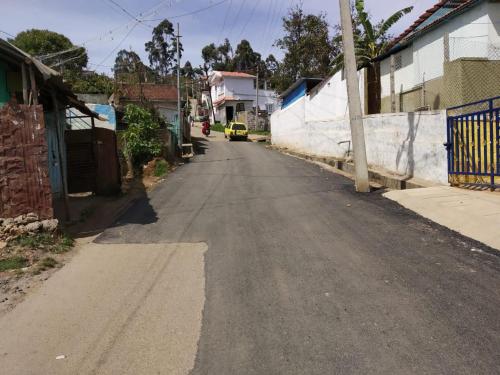 an empty street in a village with a yellow car on the road at Pears Tree Duplex Villa in Kodaikānāl