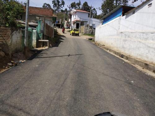 an empty street with a yellow car on the road at Pears Tree Duplex Villa in Kodaikānāl