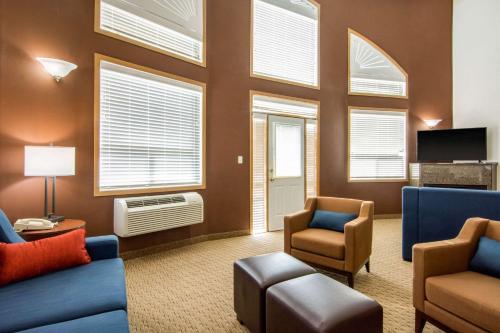a living room with a blue couch and chairs and windows at Comfort Inn & Suites in Medicine Hat