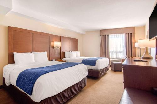 a hotel room with two beds and a desk at Comfort Inn & Suites in Medicine Hat