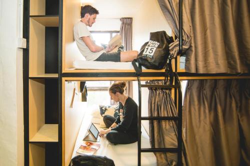 a man and a woman sitting on a bunk bed at Traveller Bunker Hostel in Cameron Highlands