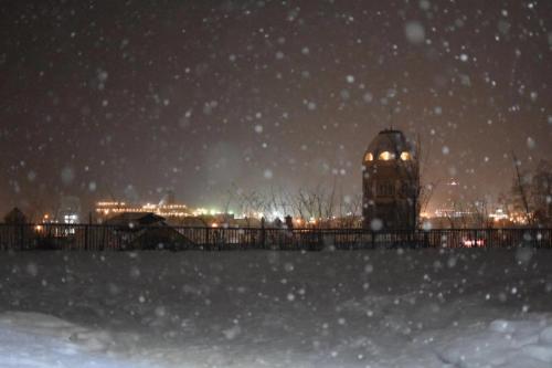 a snowy night with a building in the background at Guest House Asahi in Otaru