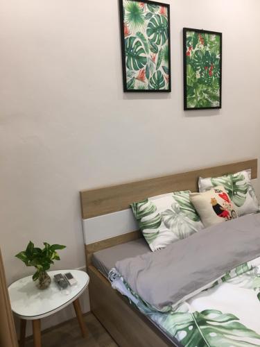 a bed with three pictures on the wall and a table at ND Happy House 1- CH sân vườn, CH chuẩn khách sạn tại số 10 ngách 5 ngõ 56 Hoa Lâm, Hà Nội in Hanoi