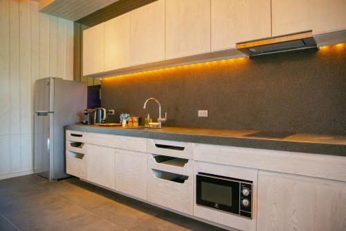 a kitchen with white cabinets and a stainless steel refrigerator at Baba Beach Club Natai Luxury Pool Villa Hotel by Sri panwa - SHA Plus in Natai Beach