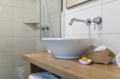 a white bowl sink on a wooden counter in a bathroom at Kronhofer – Apartments & Erlebnis-Imkerei in Hermagor