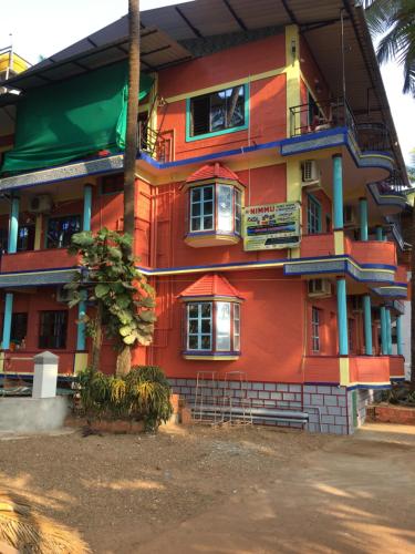 a colorful building with a tree in front of it at Nimmu Guest House & Restaurant Gokarna in Gokarna