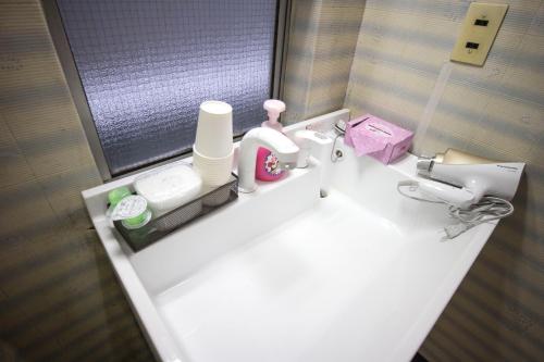 a bathroom with a sink with a toilet and a mirror at Riverside Stay Kanazawa in Kanazawa