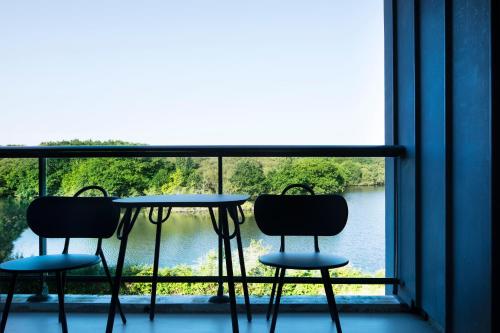 two chairs and a table in front of a window at Best Western Plus Hotel les Rives du Ter in Larmor-Plage