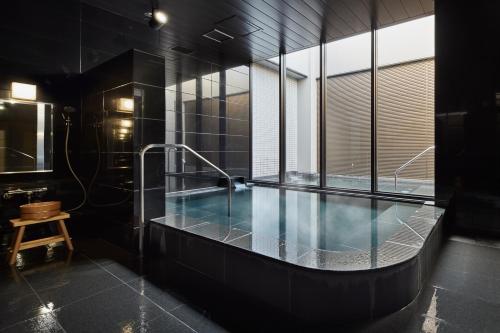 a large swimming pool in a room with black tiles at the square hotel KANAZAWA in Kanazawa