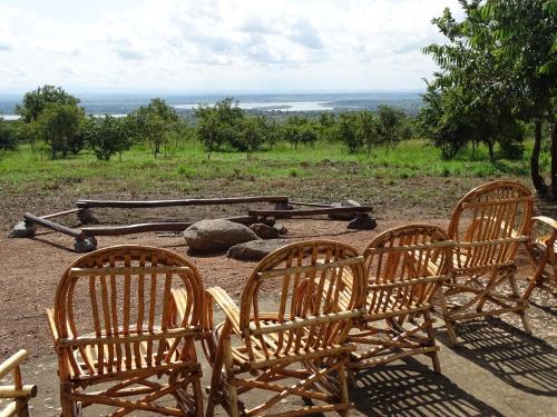a group of three chairs sitting on top of a field at Mama Washindi Lodge in Pakwach East