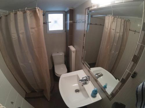 a bathroom with a sink and a toilet and a mirror at Athenian Riviera Apartment in Athens