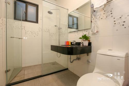 a bathroom with a glass shower and a toilet at Wuju Wusu B&B in Wenlan