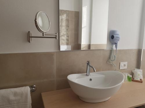 La salle de bains est pourvue d'un lavabo et d'un miroir sur un comptoir. dans l'établissement Hotel Pedretti, à Branzi