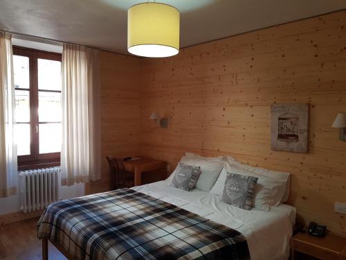 1 dormitorio con 1 cama y pared de madera en Hotel Pedretti, en Branzi