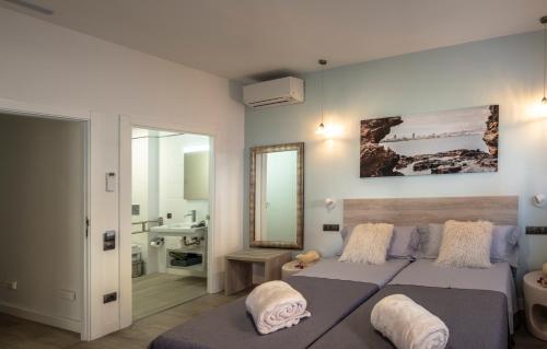a bedroom with two beds and a mirror and a sink at La Palmera Hotel Boutique in Las Palmas de Gran Canaria
