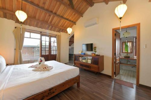 - une chambre avec un grand lit et une télévision dans l'établissement An Bang Beach Villa, à Hội An