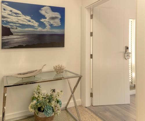 a glass table in a hallway with a painting on the wall at La Palmera Hotel Boutique in Las Palmas de Gran Canaria