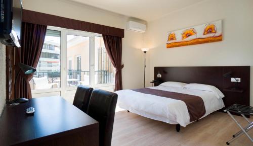 a hotel room with a bed and a desk and a window at Hotel El Pozo in Torremolinos