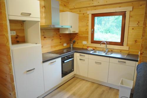 Una cocina con gabinetes blancos y un fregadero y una ventana. en Héron d'Argent, en Meurimont