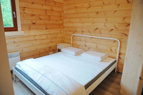- une chambre avec un lit blanc dans un mur en bois dans l'établissement Héron d'Argent, à Meurimont