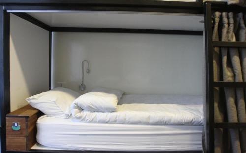 a bunk bed with white sheets and pillows on it at Hamra Urban Gardens in Beirut