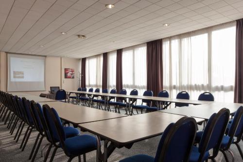 a conference room with tables and chairs and a whiteboard at The Originals City, Hôtel Le Forum, Strasbourg Nord in Schiltigheim