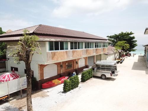 a house with a boat parked in front of it at Walking Street Hostel in Ko Lipe