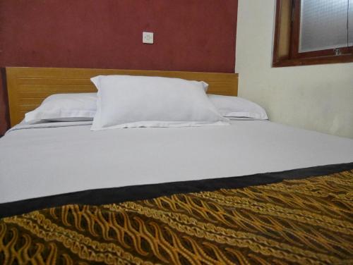 a large bed with white sheets and pillows at Rumah Tawa Hotel Syariah in Bandung