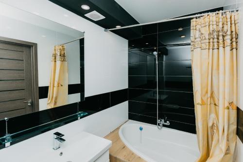 La salle de bains est pourvue d'une baignoire, d'un lavabo et d'un miroir. dans l'établissement Luxury Apartment, à Soumy