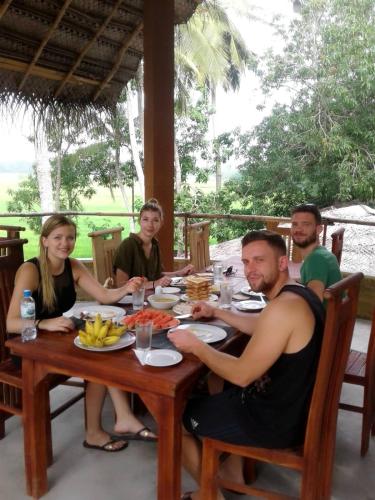 a group of people sitting around a table eating food at Rice Rice Villas in Tissamaharama