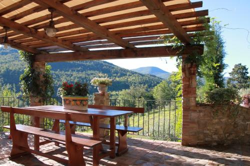 a wooden pergola with a table and a bench at Podere Piandicava in Castelnuovo di Val di Cecina