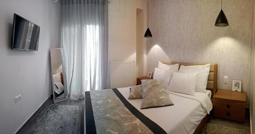 een slaapkamer met een bed met witte kussens en een televisie bij Alpinia n Lotus Apts. (Must) in Thessaloniki
