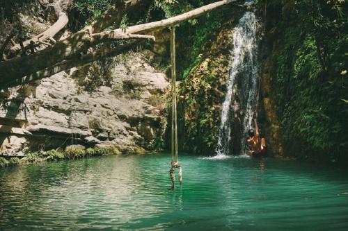 a person in the water in front of a waterfall at The Olympians Villas in Polis Chrysochous