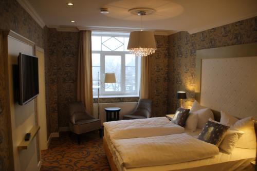 マッサーベルクにあるKurhaus Masserbergのベッド2台とシャンデリアが備わるホテルルームです。